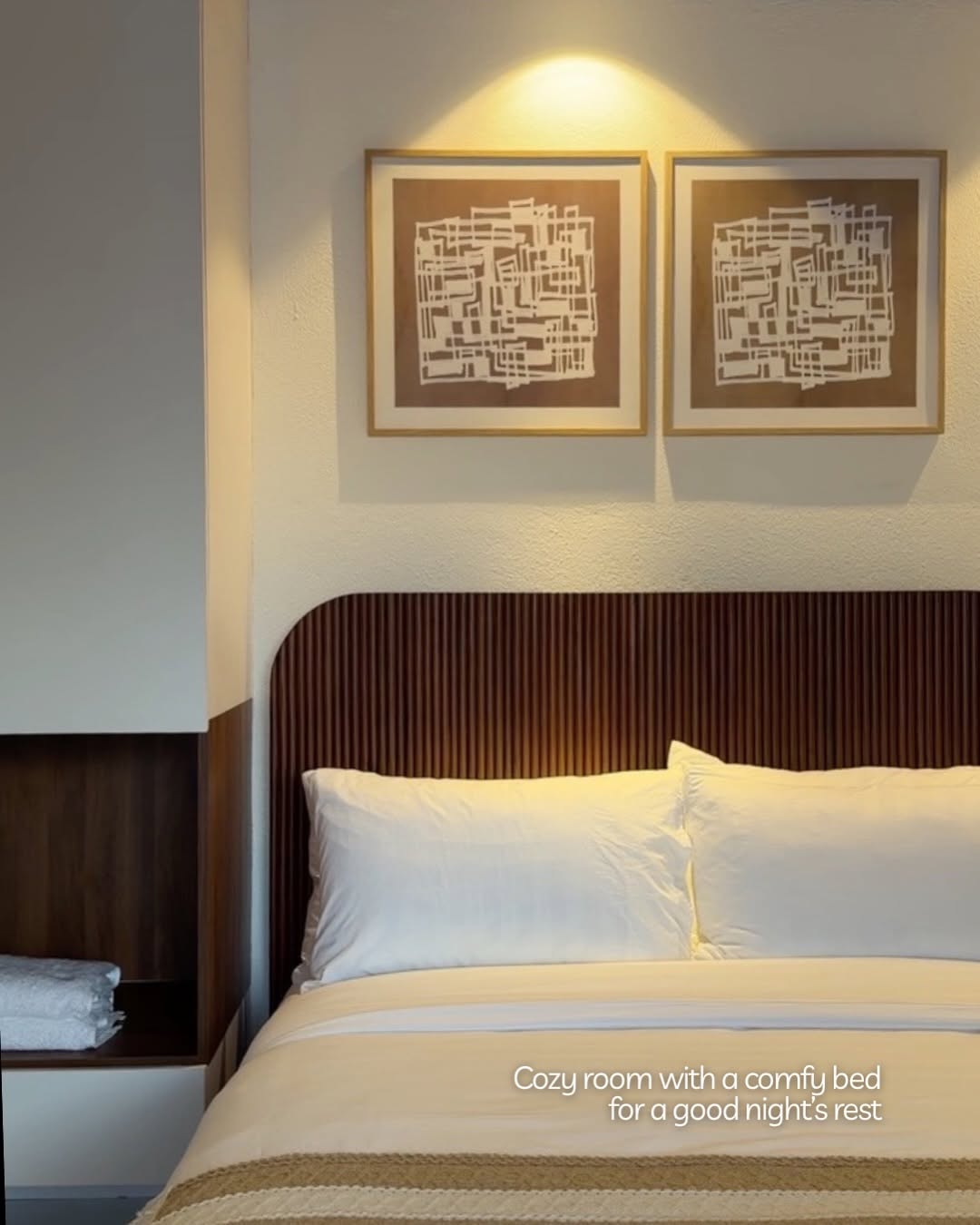 Ayatana bedroom — wooden slat headboard, crisp white linens, and framed art on the wall